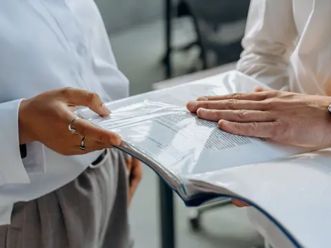 Two professionals examining business documents during an office meeting.