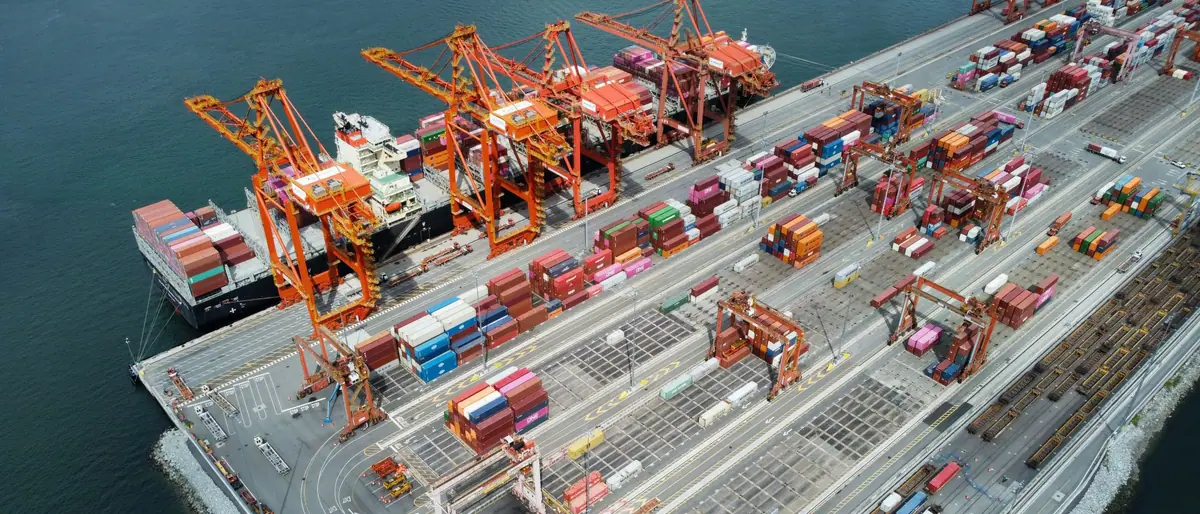 Container ship and cargo cranes operating at a busy port.